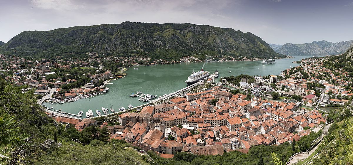 Panorama of the walled old town of Kotor and its bay below wooded mountains