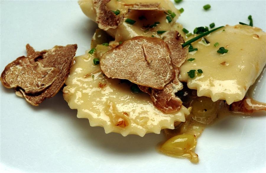 Fresh pasta topped with shaved white truffle on a white plate